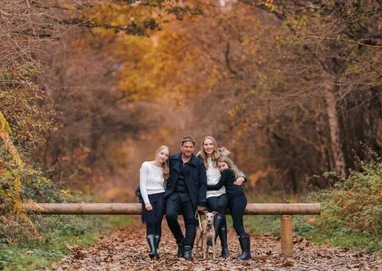 family of 4 and pet whippet dog realz infront of lovely autumnal trees in park