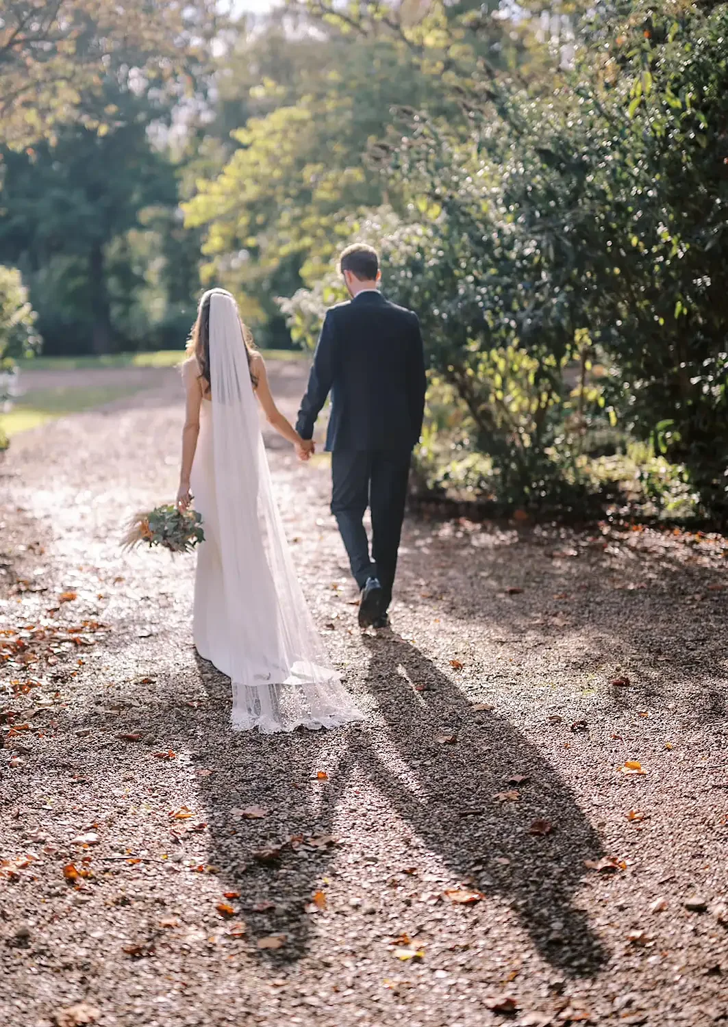 bride and groom walking into sunshine in the gardens of hodsock priory wedding photographer