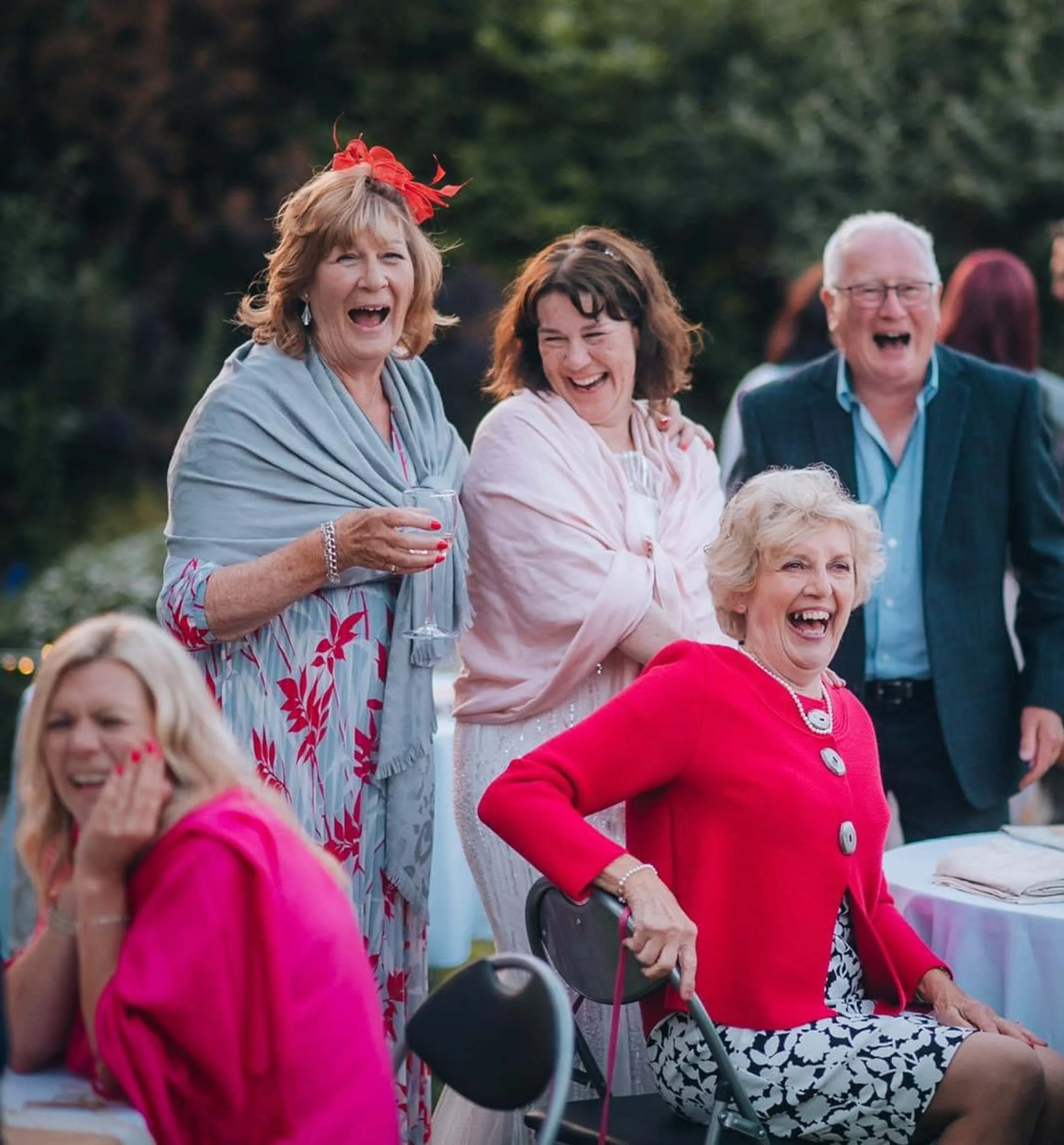 Group of cheerful elderly people at an outdoor celebration, laughing and smiling, with some holding drinks. At an outdoor thwaite mills wedding