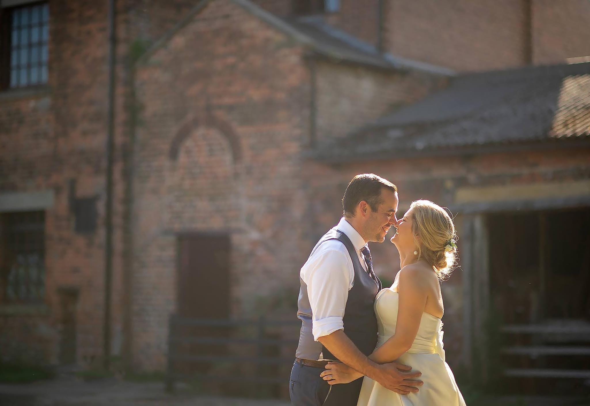 bride and groom kissing in beautiful sunshine wit old industrial buildings behind, Thwaite Mills yorkshire wedding photography