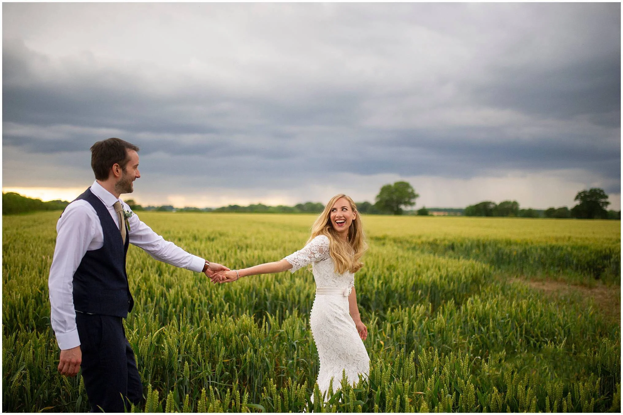 bride and groom smiling at each other walking through a farmersfield at the normans wedding venue in yorkshire
