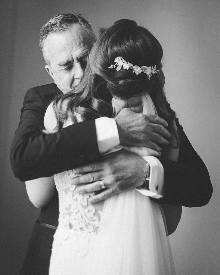 A dad holding his daughter tight on her wedding day, in black and white