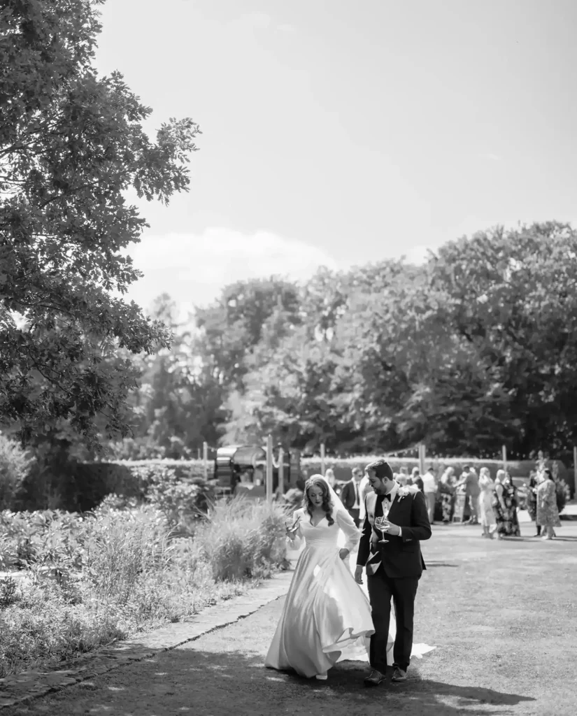 black and white photo of bride and groom strolling in gardens of cockliffe country house wedding photographer