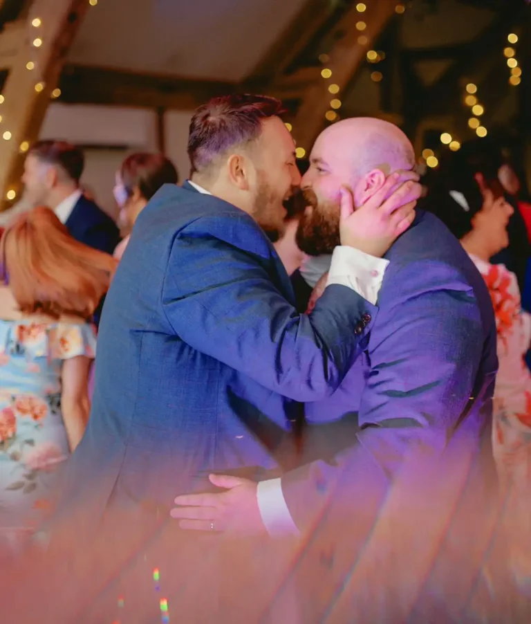 Two grooms cheek to cheek on the dance floor at Sandburn Hall