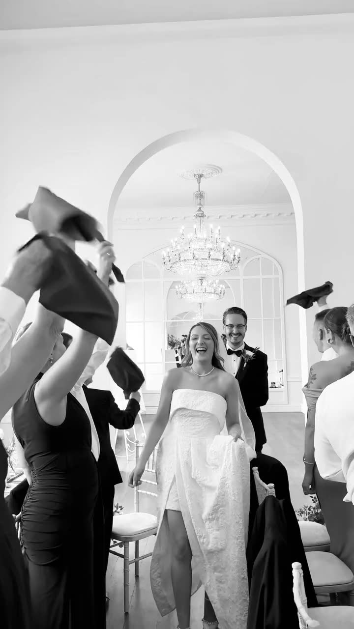 Black and white video of guests waving napkins as the bride walks into the wedding breakfast at Norwood Park